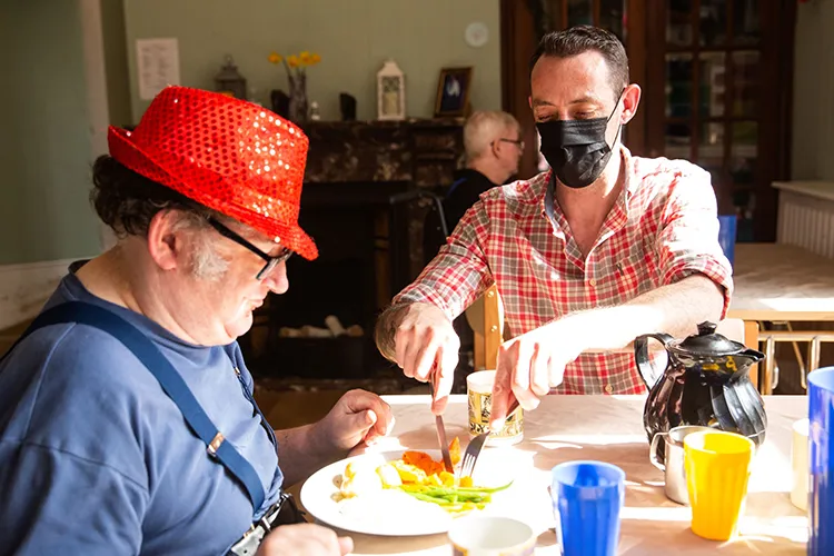 Care worker cutting up food for resident