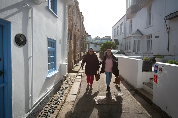 Care worker and person outside walking down a narrow street