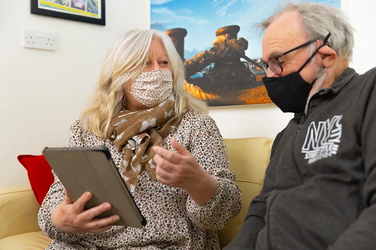 Care worker showing tablet to elderly resident