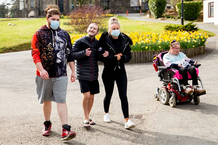 Care workers and smiling residents walking outside