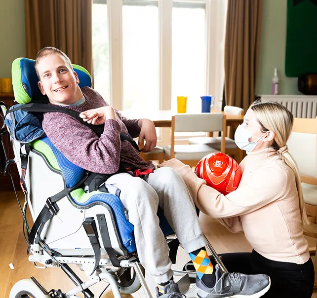 Disabled male with care worker holding a ball