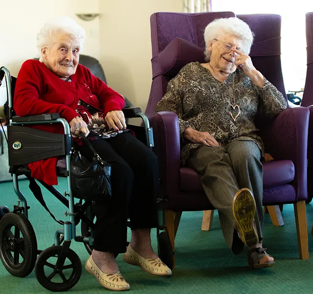 Two elderly residents sitting and laughing