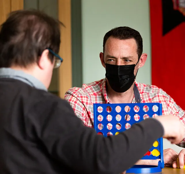 Proud to Care Cornwall Care worker and person playing a game