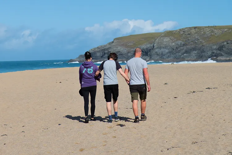 Care workers and man walking across a beach