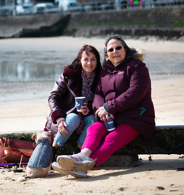 Care worker and woman smiling sitting on a beach
