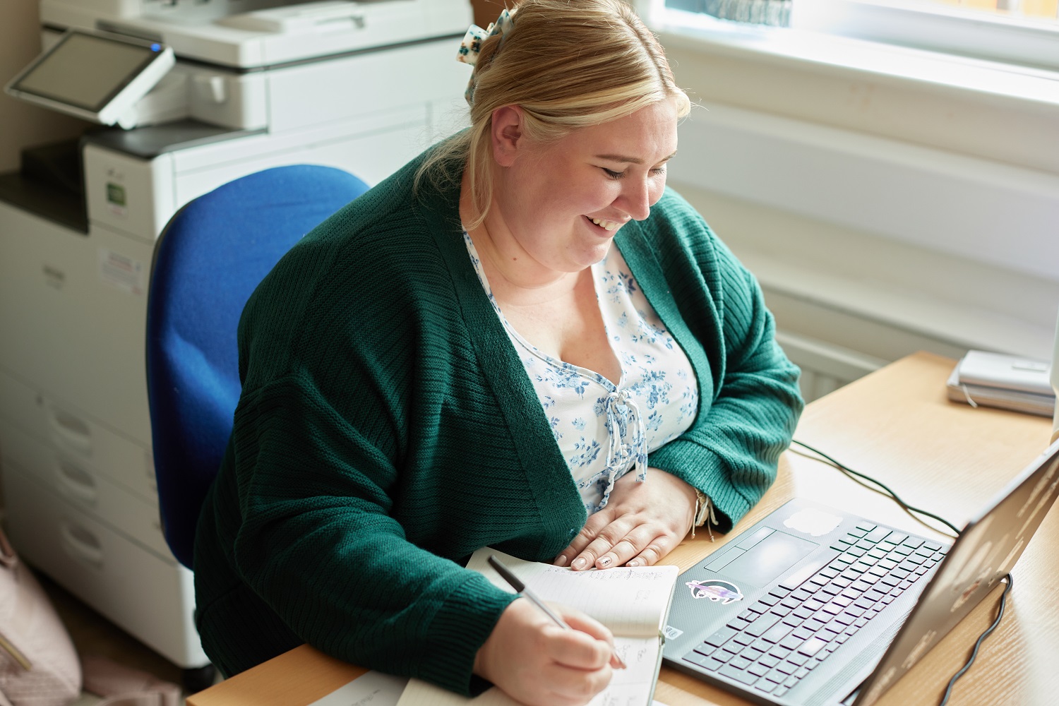 Admin worker sat at a desk smiling