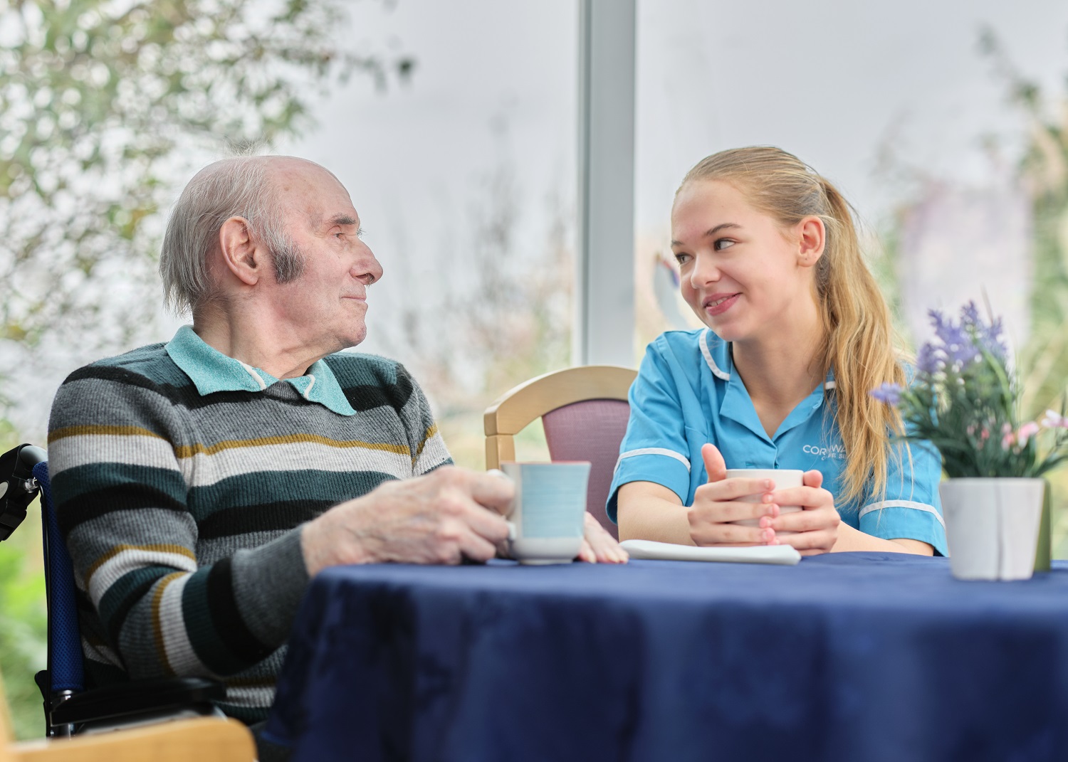 a young girl care worker smiling with an elderly gentleman