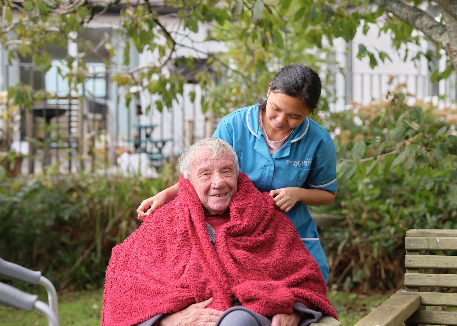 a care worker wrapping an elderly gentleman in a blanket