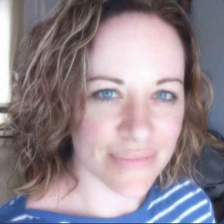 female care worker with brown hair smiling at the camera