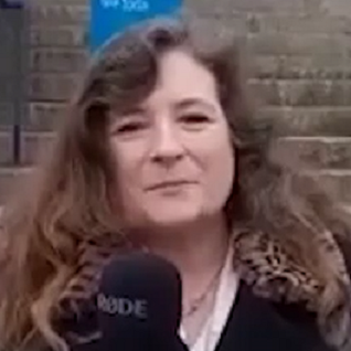 Female with long dark hair looking at the camera holding a microphone